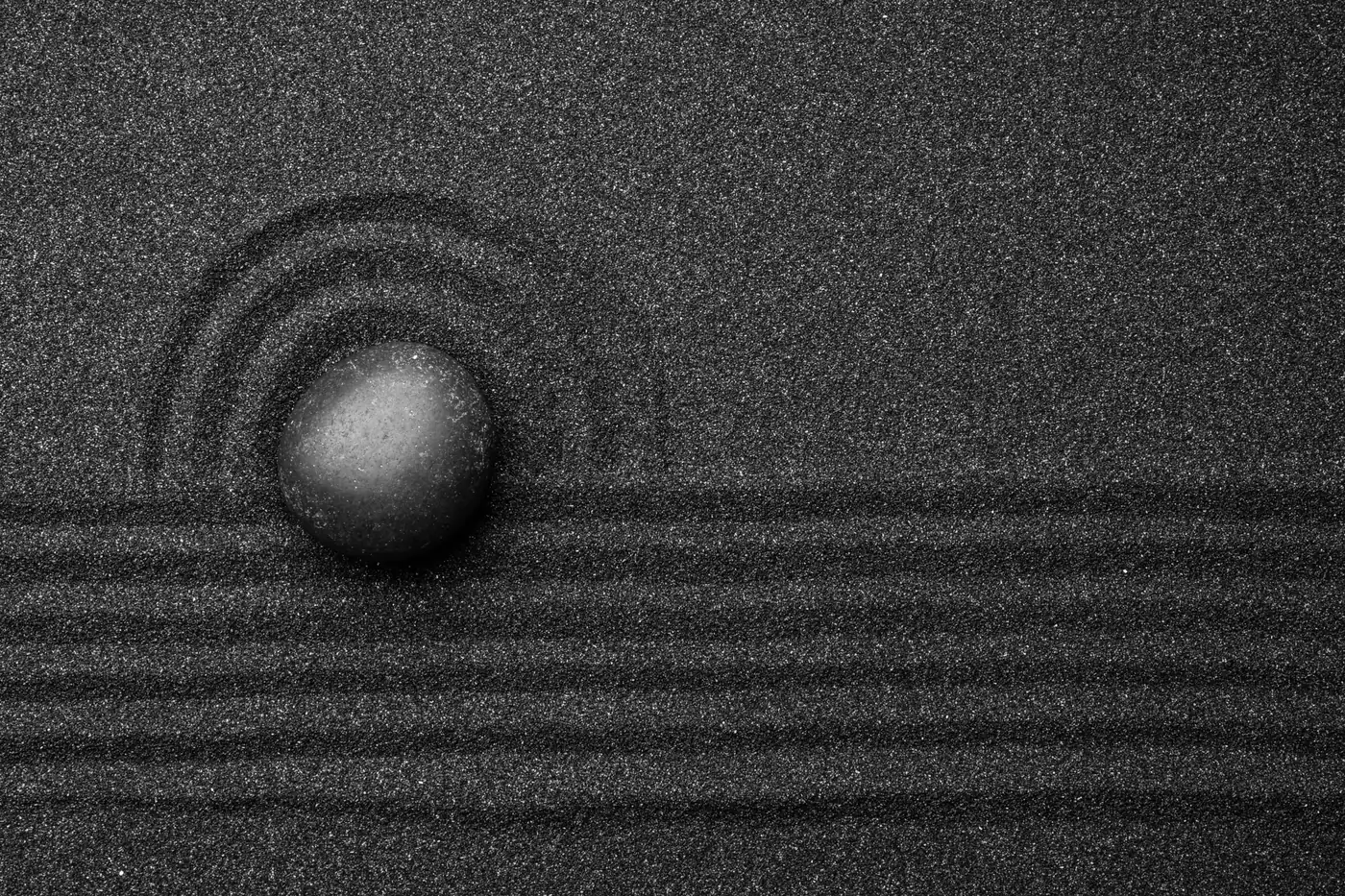 A smooth stone on raked black sand
